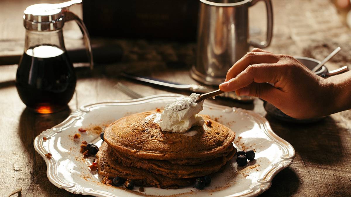 person putting butter on pancakes